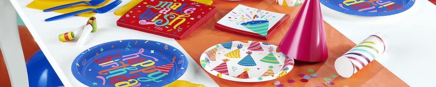Paper plates, napkins and a party hat laid out on a table